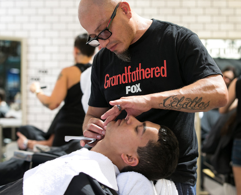 A barber from Rudy's Barbershop treats a guest to a free shave at the Grandfathered Pop-Up Barbershop, promoting the new FOX show.