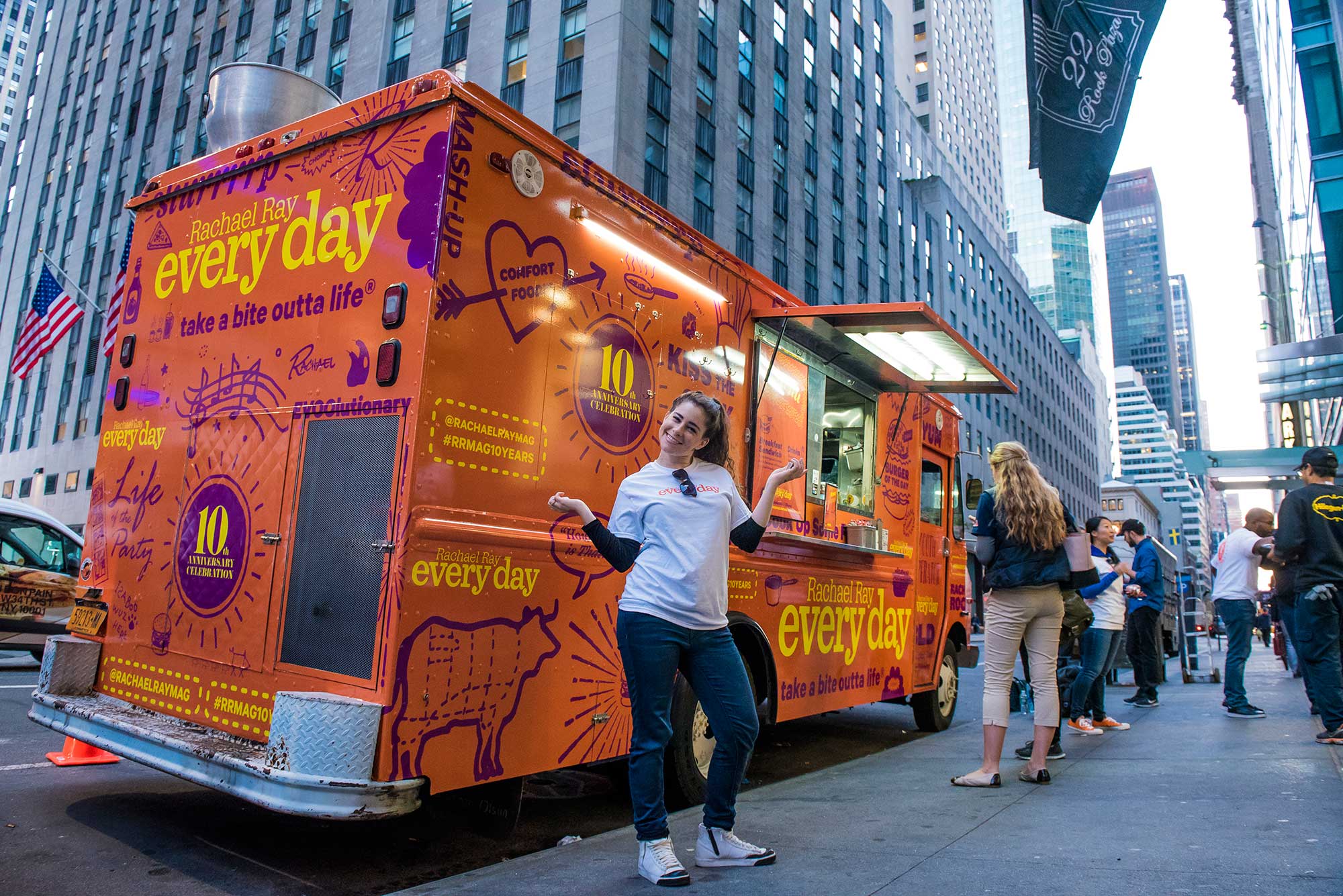 A Brand Ambassador poses with the Rachel Ray Every Day food truck, where guests received free burgers and branded sunglasses.